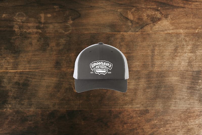 Smooshies branded embroidered trucker hat on a wood table.